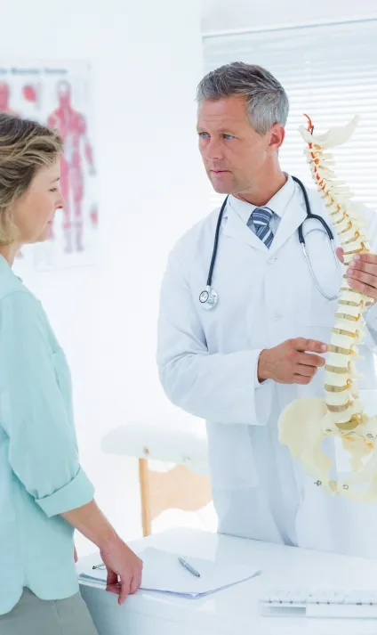 Profissional de saúde mostrando um modelo da coluna vertebral a uma paciente